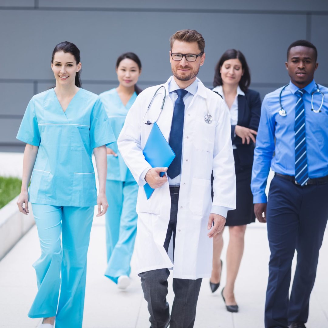 Team of doctors walking in a row in hospital premises